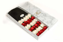 A close-up of 30 roses in a luxury marble box by Vancouver's Box des Fleeurs. The arrangement has an alternating color combination of red and white roses.