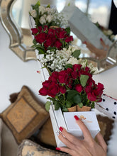 A close-up of an arrangement of white and red roses with baby's breaths and greenery in a marble box from Vancouver's Box des Fleurs. This arrangement fits the flowers in ice-cream cones, crating a very unique arrangement. 