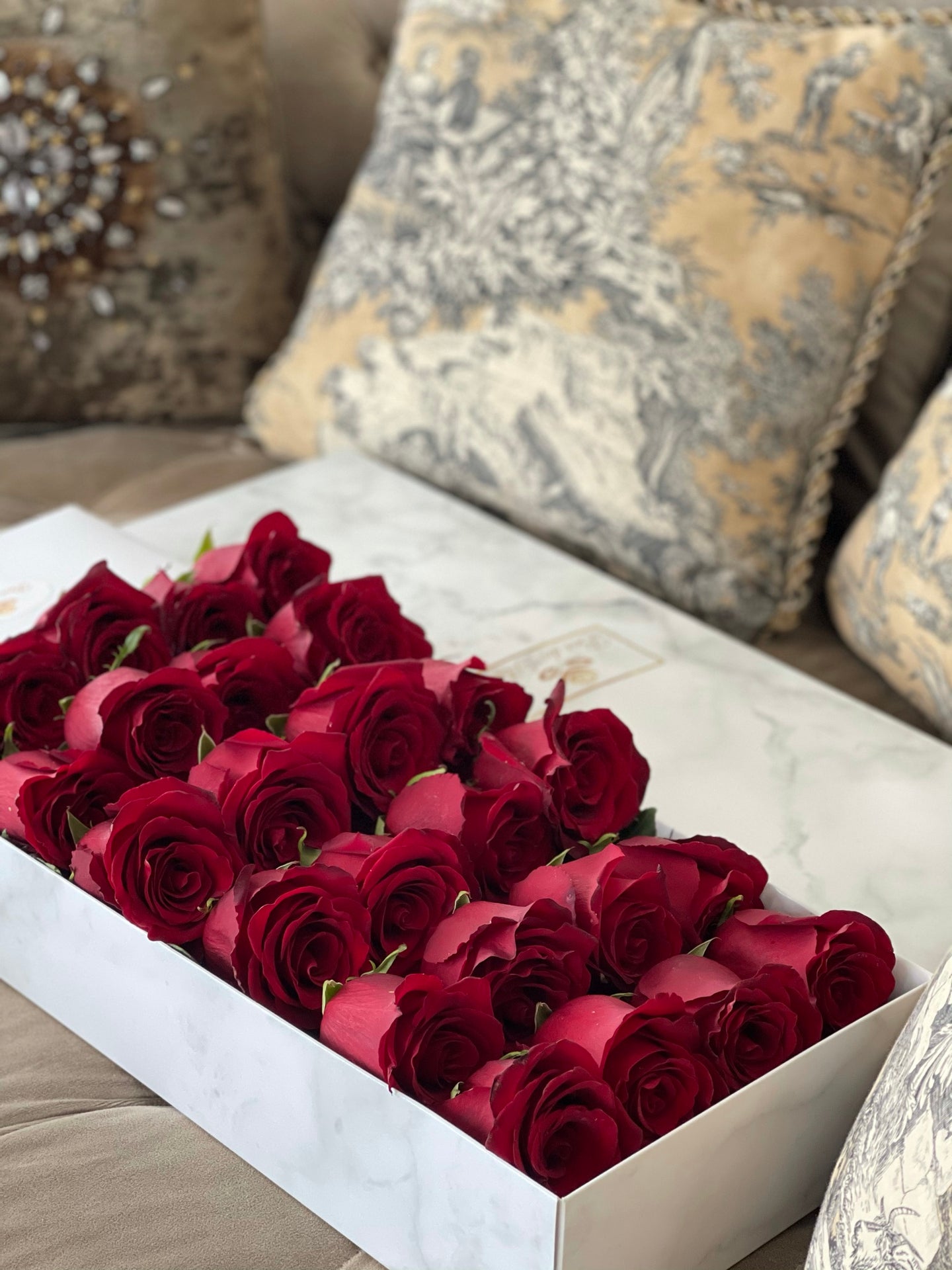 A close-up image of 24 red roses from Vancouver's Box Des Fleurs in a Luxury Marble Box. The elegant white marble complements the rose's natural beauty. Perfect for a sophisticated and romantic gift or decoration. Order now for fresh, handcrafted flowers from Vancouver's premier florist.
