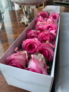 A close-up view of a dozen stunning magenta pink roses arranged by Vancouver's Box Des Fleurs. Each rose features delicately curled petals that showcase their natural beauty. This elegant bouquet makes the perfect gift to add sophistication and romance to any space. Order now for fresh, handcrafted flowers from Vancouver's premier florist.
