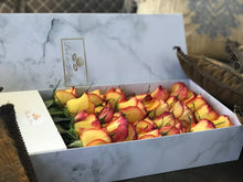 A close-up image of 24 orange to yellow ombre roses from Vancouver's Box Des Fleurs in a Luxury Marble Box. The elegant white marble complements the rose's natural beauty. Perfect for a sophisticated and romantic gift or decoration. Order now for fresh, handcrafted flowers from Vancouver's premier florist.