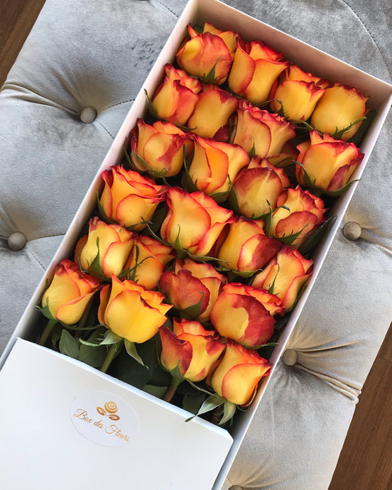 A close-up image of 24 beautiful yellow to orange ombre roses from Vancouver's Box Des Fleurs in a Luxury Marble Box. The Infini's arrangement of roses symbolizes the infinity sign with the stems meeting in the middle in an elegant white marble box, adding a touch of sophistication to any space. Order now for fresh, handcrafted flowers from Vancouver's premier florist.