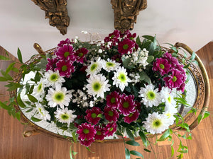 A close-up of a collection of pink/ purple and white daisies with baby's breaths and stunning greenery. 