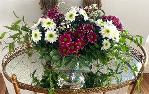 A close-up of a collection of pink/ purple and white daisies with baby's breaths and stunning greenery. 