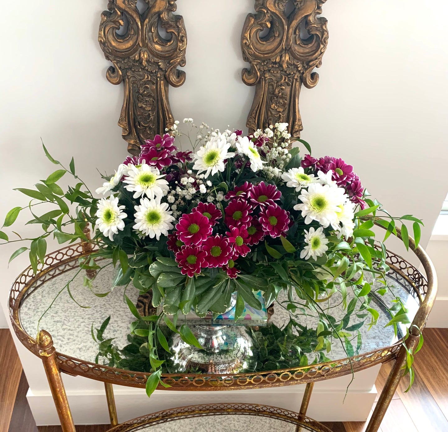 A close-up of a collection of pink/ purple and white daisies with baby's breaths and stunning greenery. 